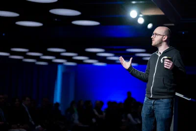 Chris presenting on stage at GitHub Galaxy London 2024, gesturing mid-talk
